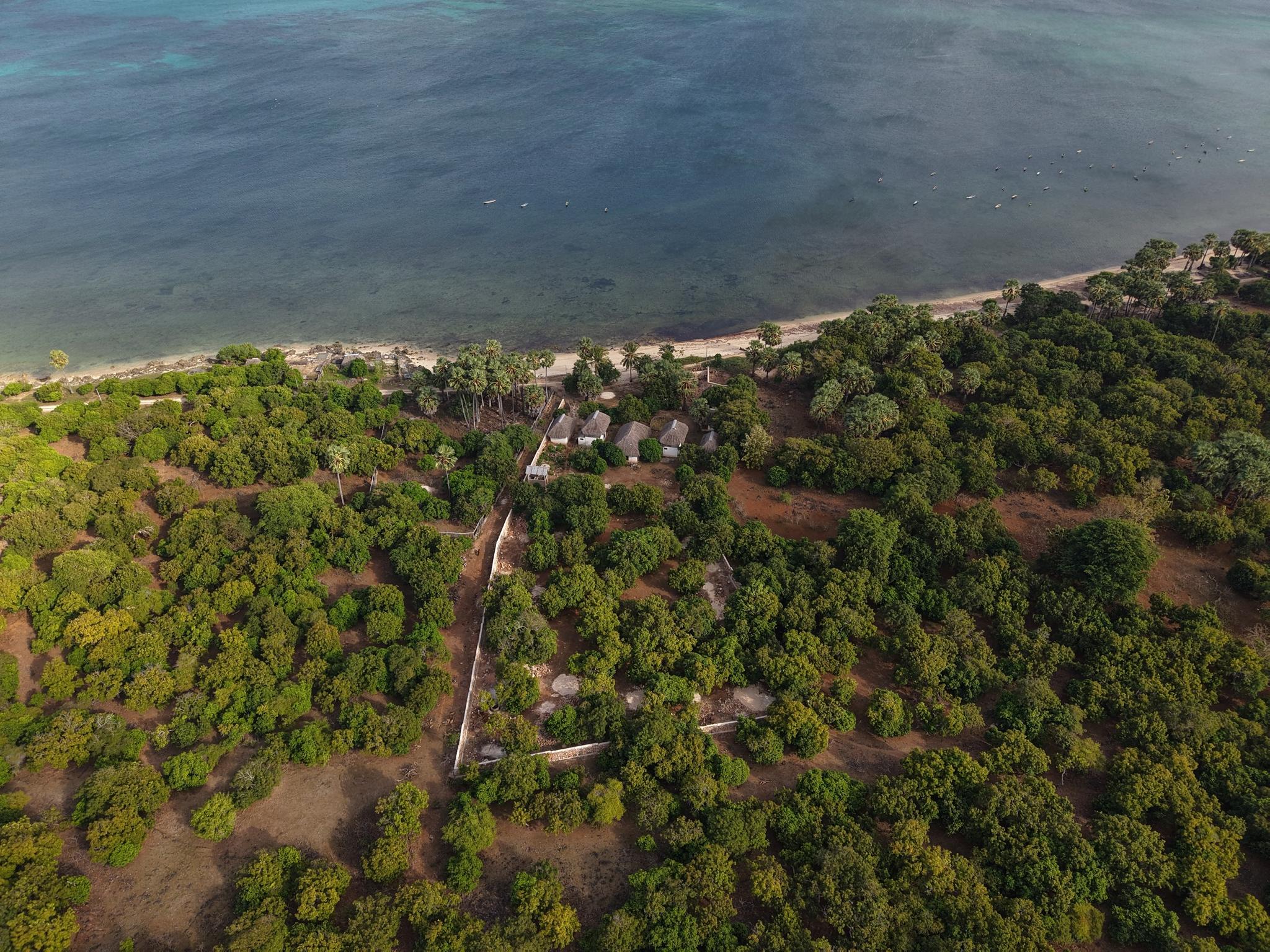 Aerial view of the turquoise reef flat and sandy beach in front of the plot